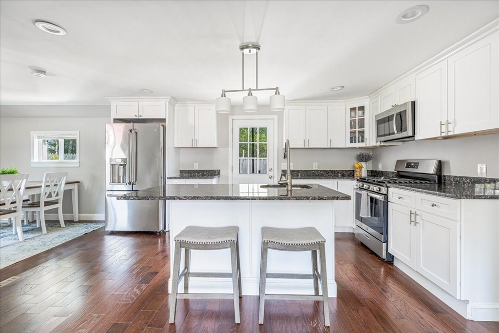 299 Cotuit Road Mashpee, MA 02649 - Photo 8 of 33 a kitchen with stainless steel appliances a stove a sink dishwasher a refrigerator and white cabinets with wooden floor