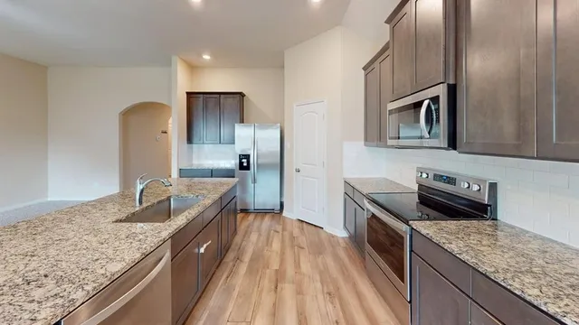 a kitchen with granite countertop stainless steel appliances sink stove microwave and cabinets