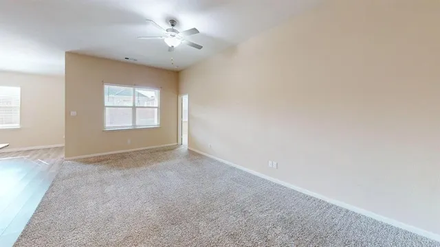an empty room with windows and chandelier fan