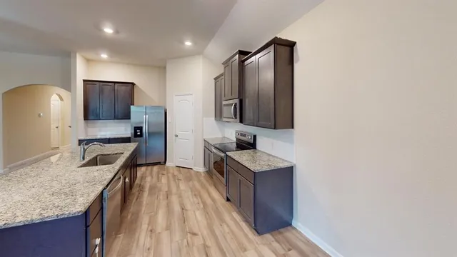 a large kitchen with kitchen island a sink dishwasher a stove and a refrigerator with wooden floor