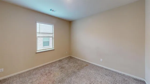 an empty room with a chandelier fan and windows