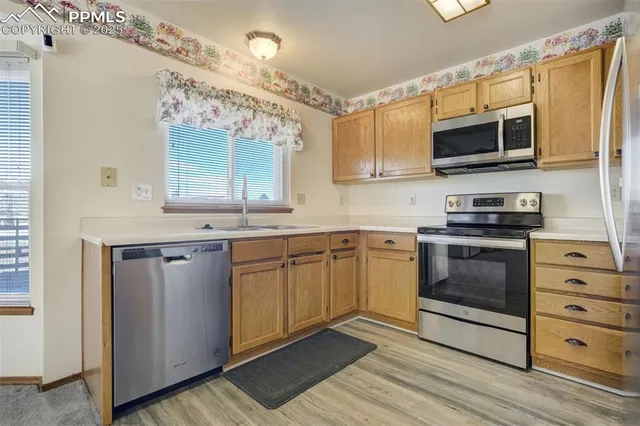 a kitchen with stainless steel appliances granite countertop a refrigerator a sink a stove a washer dryer and a refrigerator