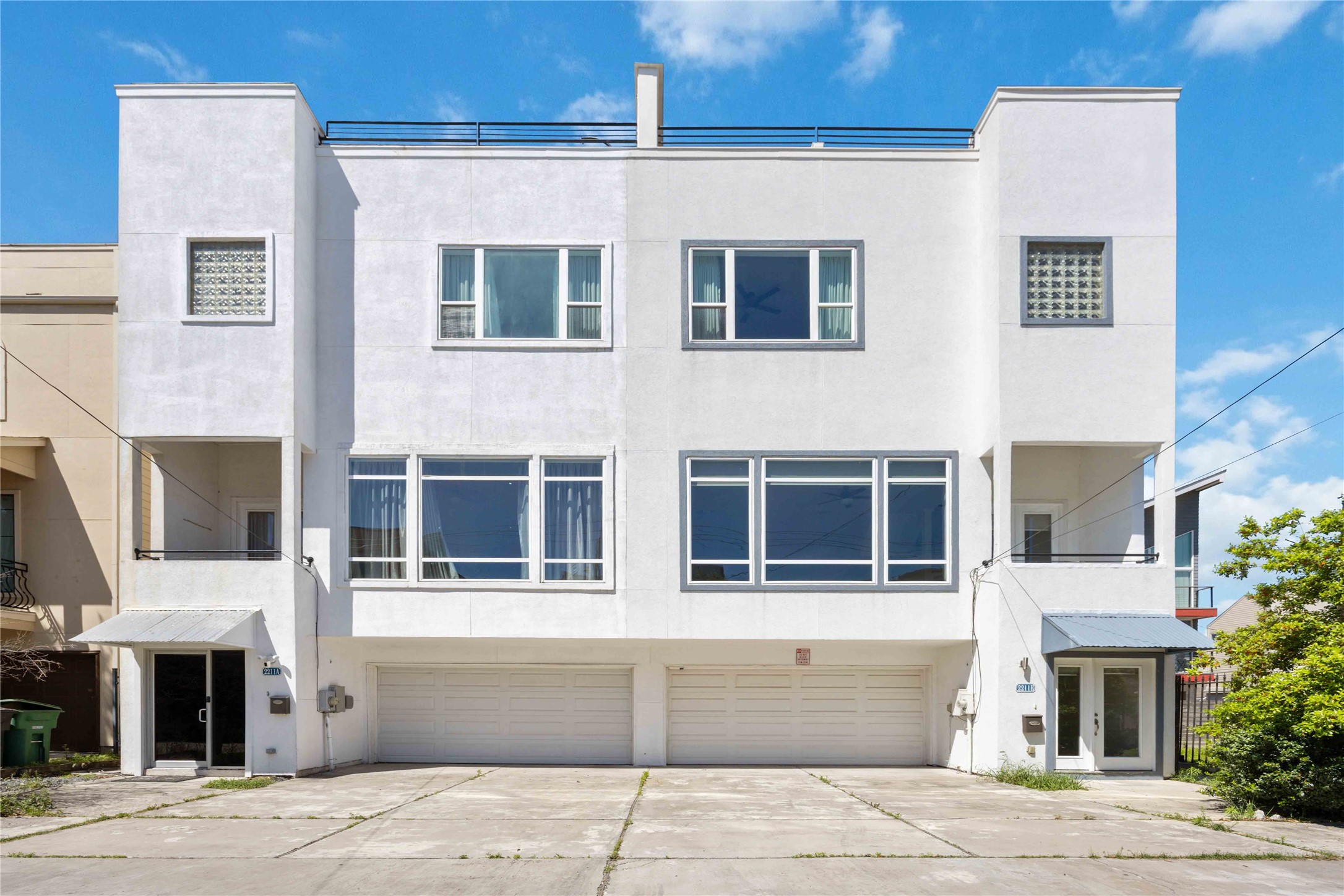 Welcome Home!! Modern Four-story townhouse with a clean white facade, large windows for natural light, and two garages. The driveway offers ample parking space.