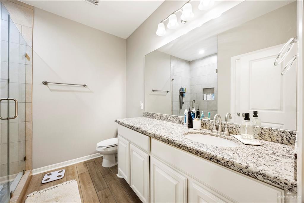 6332 Cascada Bnd Road McAllen, TX 78504 - Photo 7 of 18 a bathroom with a granite countertop sink a toilet and a mirror