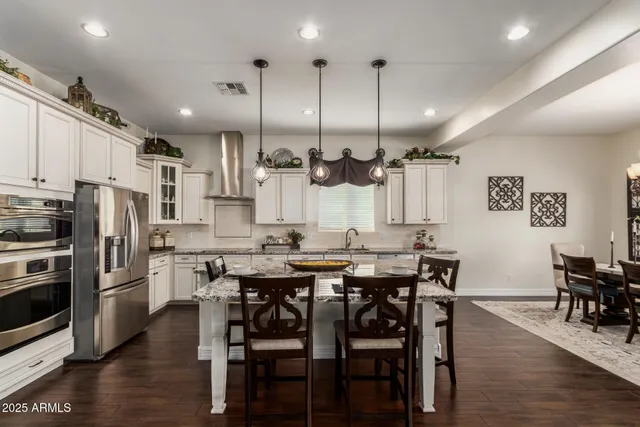 a kitchen with stainless steel appliances kitchen island granite countertop a kitchen island hardwood floor and a sink