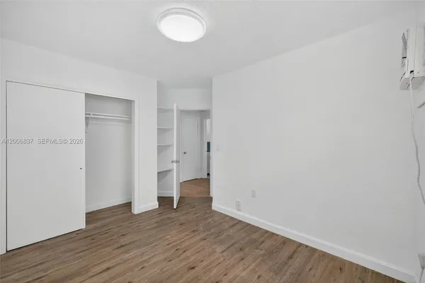 a view of an empty room with wooden floor and closet