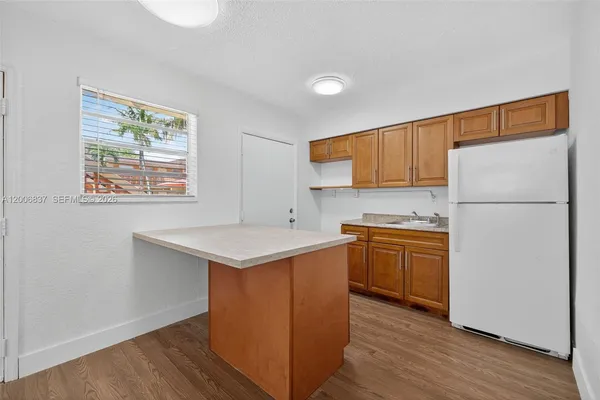 a kitchen with a refrigerator a stove a sink and wooden floor