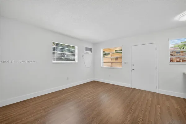 an empty room with wooden floor and windows