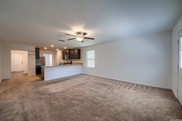 an empty room with chandelier fan and windows