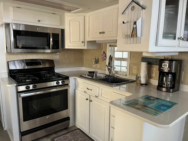 a living room with stainless steel appliances kitchen island granite countertop a refrigerator and a stove top oven