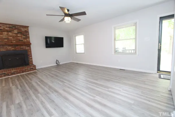 a view of a livingroom with a fireplace a ceiling fan and windows