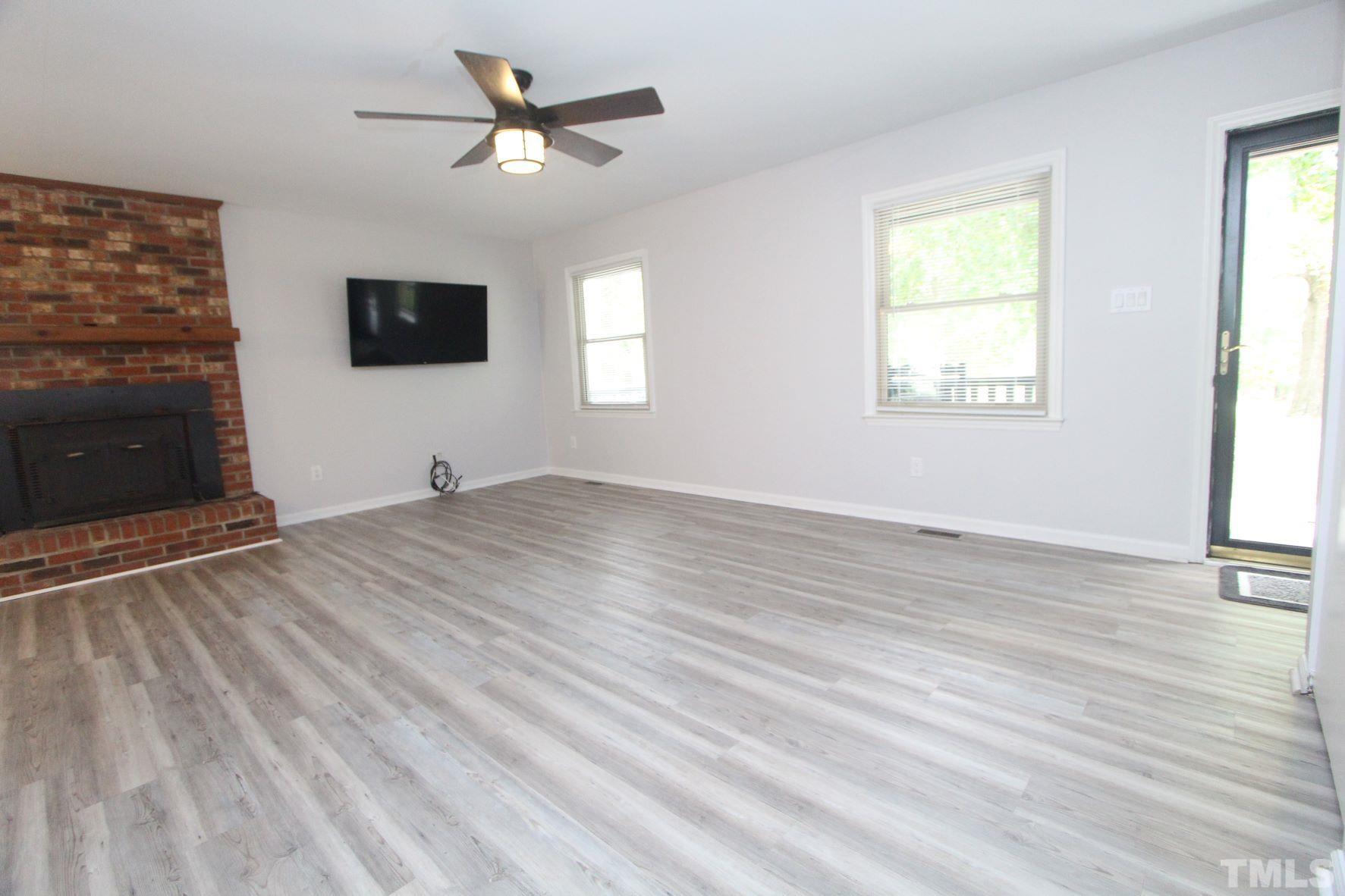 4161 Range Road Stem, NC 27581 - Photo 11 of 43 a view of a livingroom with a fireplace a ceiling fan and windows