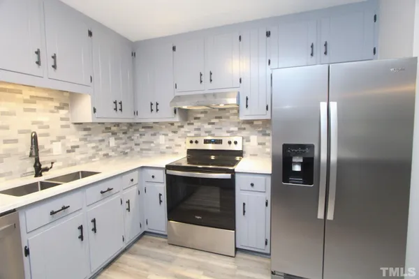 a kitchen with stainless steel appliances granite countertop a refrigerator stove and white cabinets