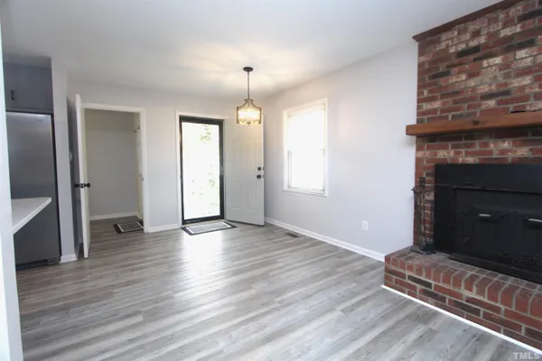 an empty room with wooden floor a fireplace and windows
