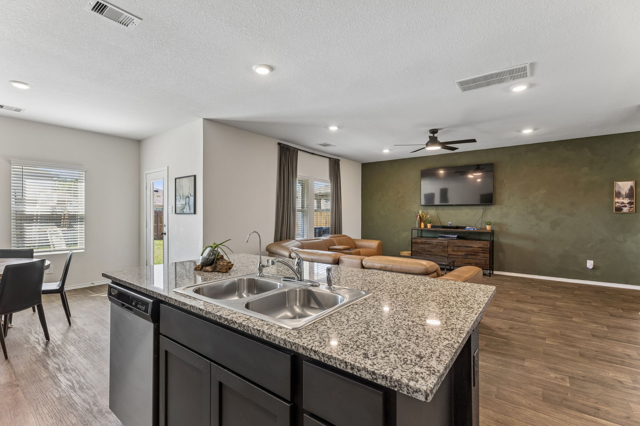 343 Sickle Loop Kyle, TX 78640 - Photo 14 of 40 Kitchen island featuring a double basin stainless steel sink, a stainless steel dishwasher, and a light-toned granite countertop