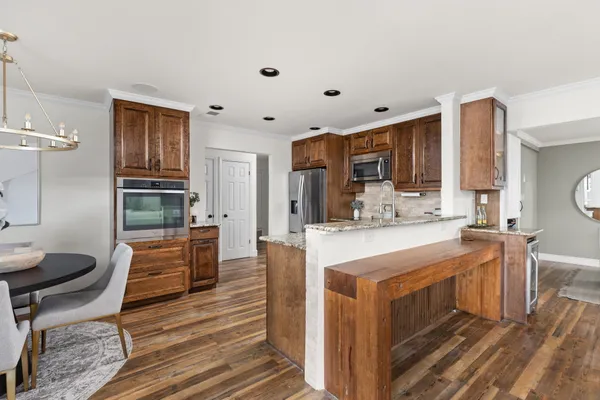 a large kitchen with stainless steel appliances kitchen island granite countertop a table chairs in it and wooden floors