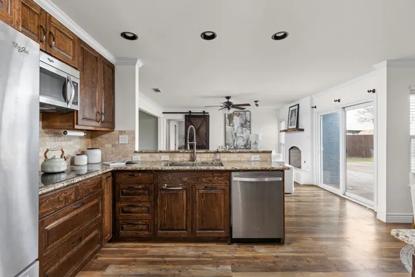 a kitchen with stainless steel appliances granite countertop a sink and wooden cabinets
