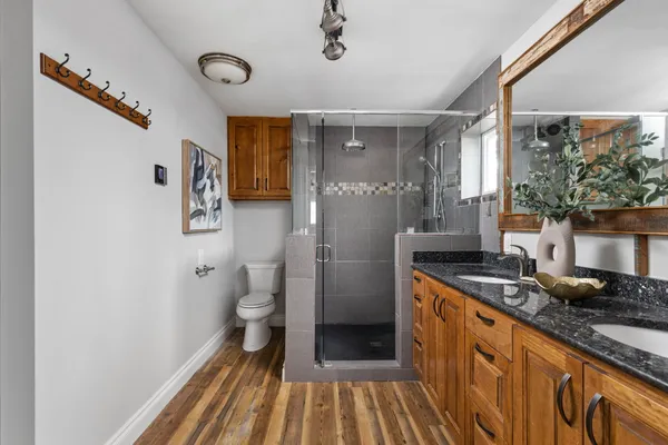 a bathroom with a granite countertop sink a toilet a mirror and a shower