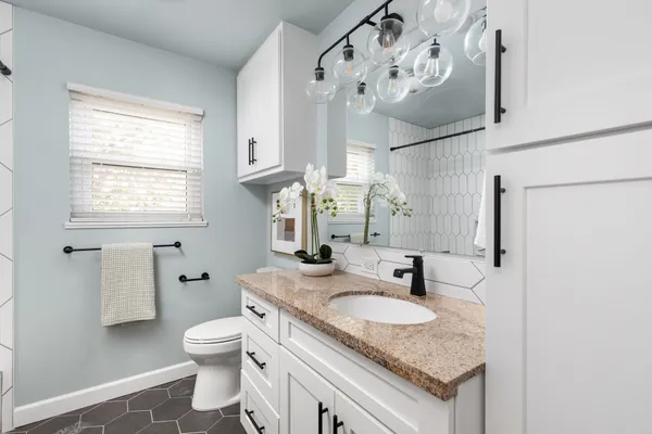 a bathroom with a granite countertop sink a toilet and a mirror