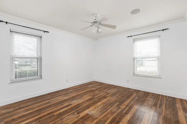 a view of an empty room with wooden floor and a window