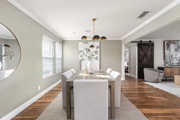 a dining room with wooden floor a chandelier a wooden table and chairs