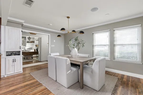 a dining hall with granite countertop a stove a sink dishwasher and a dining table with wooden floor