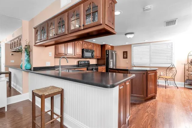 a kitchen with stainless steel appliances granite countertop a table chairs in it and wooden floors