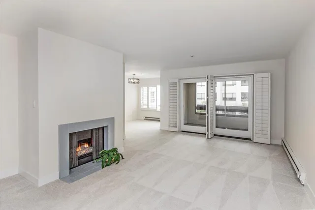 an empty room with windows and fireplace