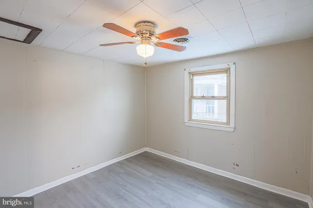 an empty room with wooden floor chandelier and windows