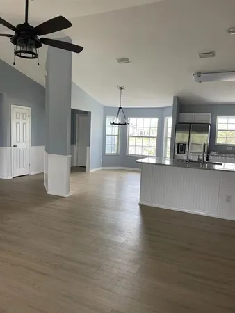 a view of a kitchen with a kitchen island stainless steel appliances wooden floor and window