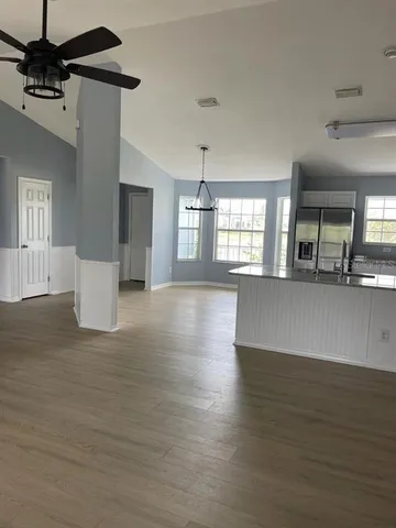 a view of a kitchen with a kitchen island stainless steel appliances wooden floor and window