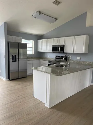 a kitchen with stainless steel appliances granite countertop a stove a sink and a microwave