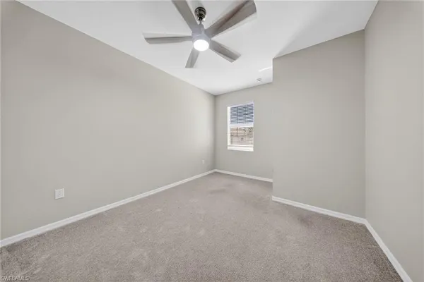 an empty room with a ceiling fan and a window