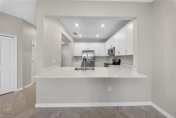 a large white kitchen with kitchen island a sink stainless steel appliances and cabinets