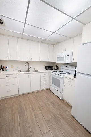 a kitchen with cabinets a sink and white appliances
