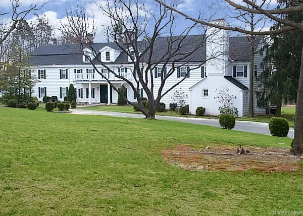 a view of a white house with a big yard and large trees