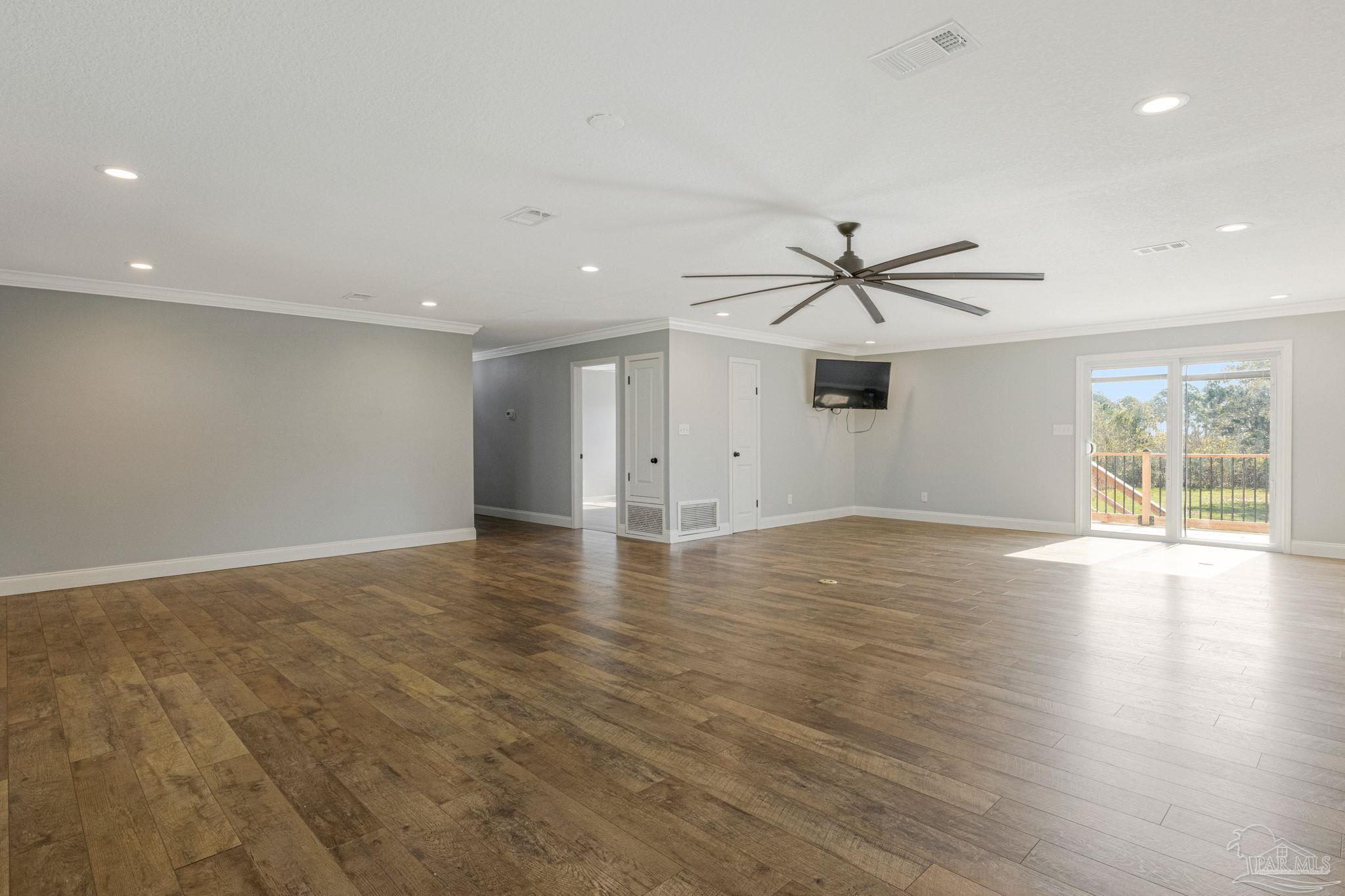 302 Garcon Point Road Milton, FL 32583 - Photo 16 of 51 an empty room with wooden floor ceiling fan and windows
