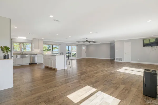 an empty room with wooden floor fan and windows