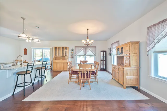 a dining room with wooden floor a chandelier a wooden table and chairs