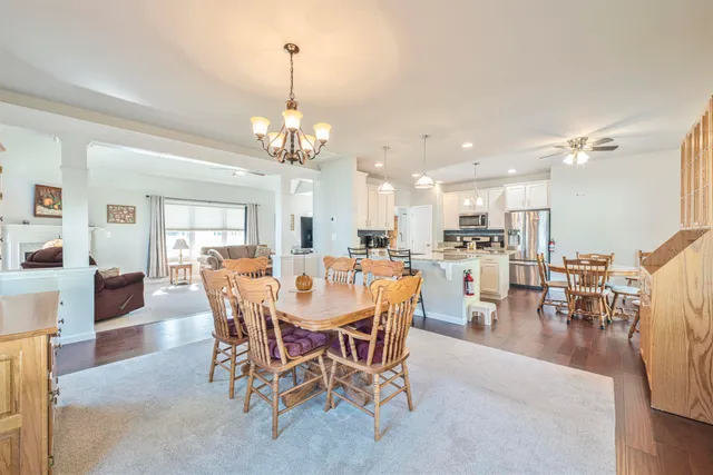 a dining room with furniture a chandelier and kitchen view