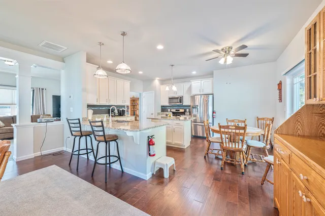 a kitchen with stainless steel appliances a dining table chairs stove and white cabinets