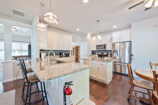 a kitchen with kitchen island granite countertop stainless steel appliances cabinets a sink and a center island