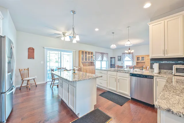 a kitchen with stainless steel appliances granite countertop hardwood floor sink stove dining table and chairs