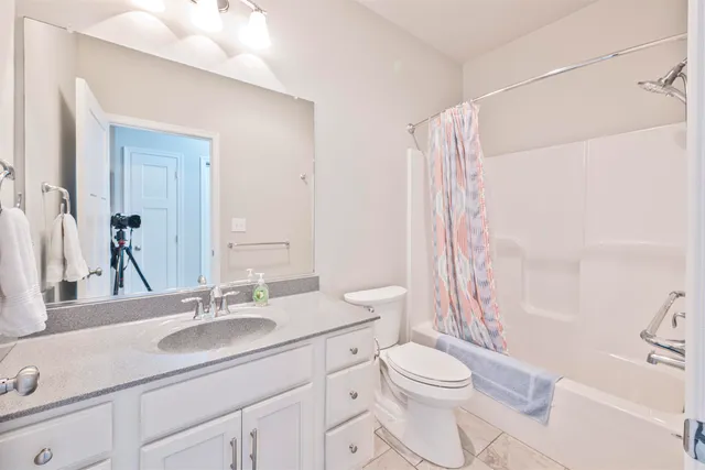 a bathroom with a sink a toilet a mirror a vanity and shower