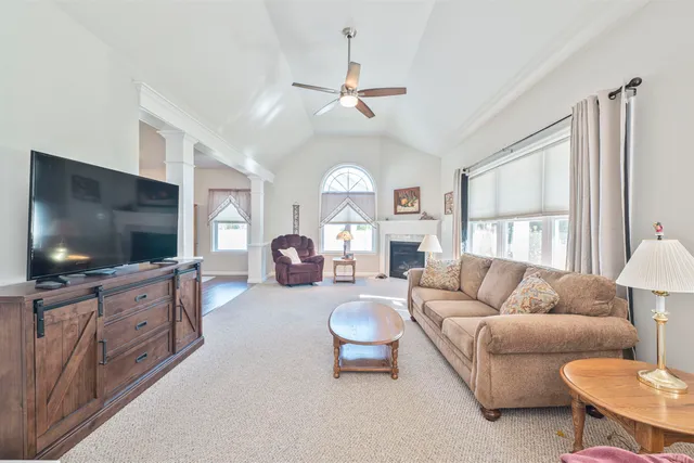 a living room with furniture a flat screen tv and a large window
