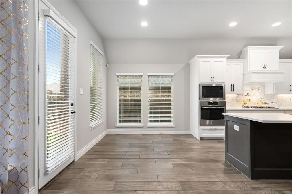 1501 Calcot Lane Forney, TX 75126 - Photo 15 of 34 Spacious open-concept area featuring wood-finish flooring, recessed lighting, and a kitchen with white cabinetry and stainless steel appliances