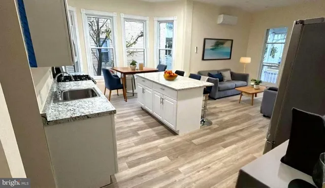 a living room with stainless steel appliances furniture a fireplace and a flat screen tv