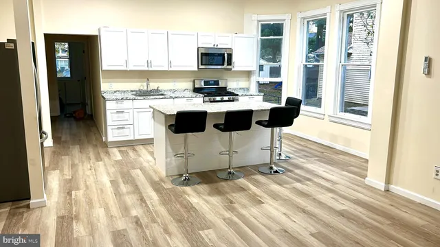 a kitchen with stainless steel appliances kitchen island granite countertop a refrigerator and a sink