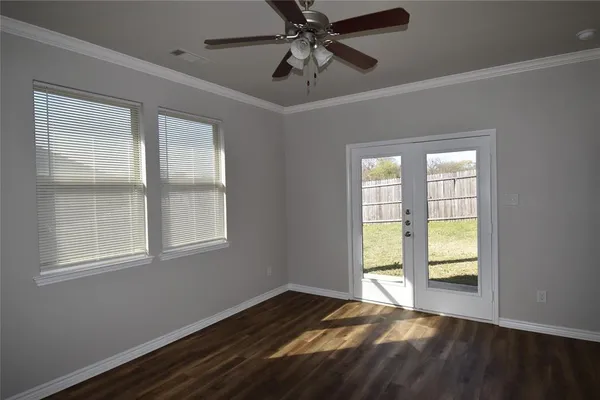a view of an empty room with a window and wooden floor