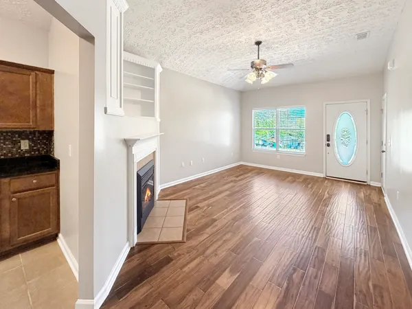 wooden floor in an empty room with a fireplace and a window